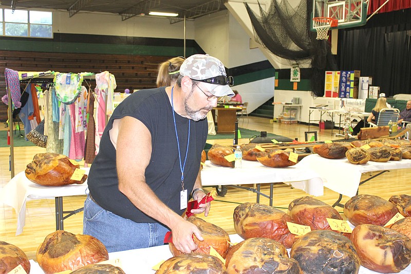 Volunteer Bill McCubbin of Holts Summit places ribbons on hams Thursday afternoon at the Callaway Youth Expo in Auxvasse. The annual Country Ham Breakfast will be held at 7:30 a.m. Saturday morning in the cafeteria at Auxvasse Elementary School. The ham sale will take place at 7 p.m. Saturday at the Auxvasse Lion's Club Park.