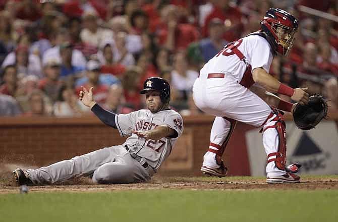 Houston Astros' Jose Altuve (27) slides safely into home as St. Louis Cardinals catcher Tony Cruz waits for a throw in the seventh inning of a baseball game on Wednesday, July 10, 2013, in St. Louis.