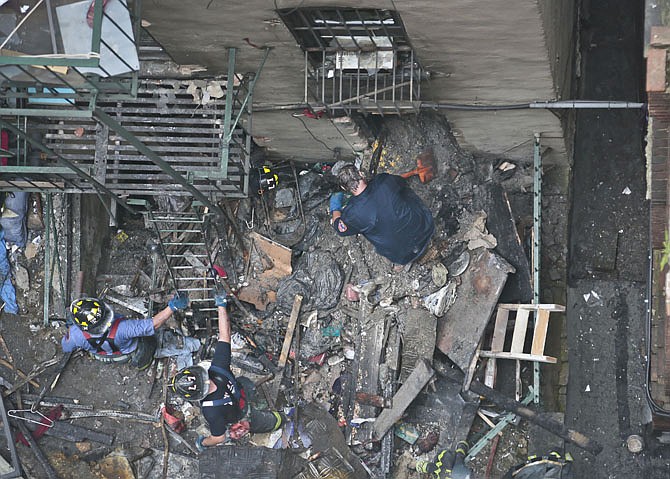 Firefighters remove debris from the back of a building in the aftermath of a fire on Thursday in New York City's Chinatown.