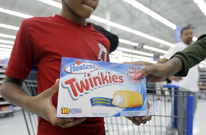 At the self checkout, Shawn Hall, 9, hands his mother Danica Streeter a box of Twinkies at Wal-Mart, Friday, July 12, 2013, in Bristol, Pa. The world's largest retailer announced Friday that that they are making Twinkies available this weekend, even though Hostess says it asked retailers to wait until Monday to start selling the spongy yellow snack cakes.