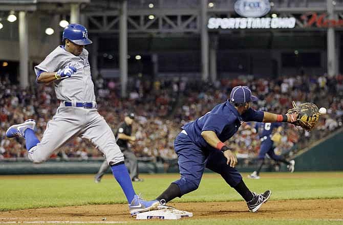 Kansas City Royals' Alcides Escobar, left, beats the throw to Cleveland Indians first baseman Carlos Santana for a bases-loaded infield single to drive in two runs in the seventh inning of a baseball game Saturday, July 13, 2013, in Cleveland. 
