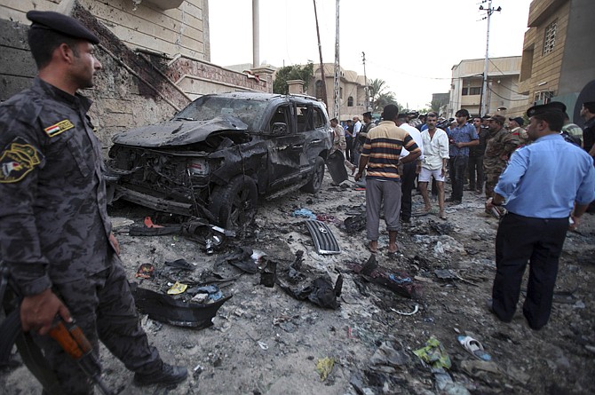 Security forces inspect the scene of a car bomb attack Sunday in Basra, 340 miles southeast of Baghdad, Iraq. A wave of explosions tore through overwhelmingly Shiite cities south of Baghdad shortly before the Muslim faithful broke their Ramadan fasts.