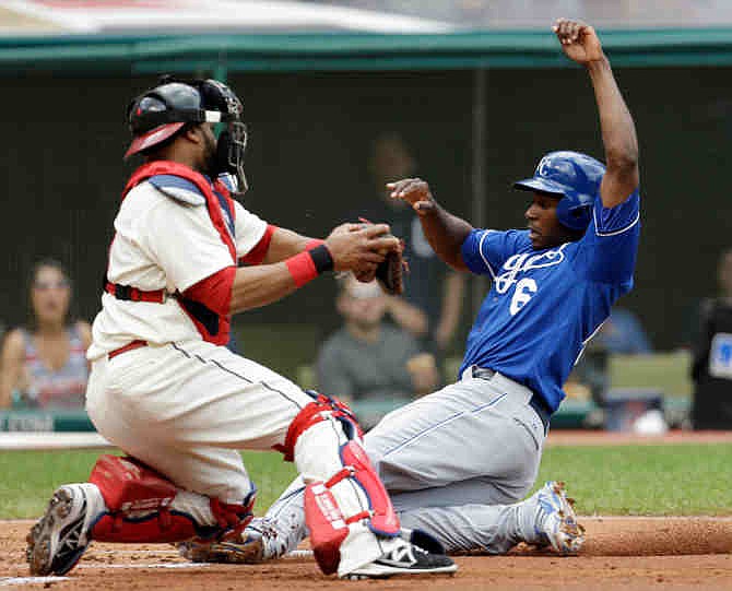 Kansas City Royals' Lorenzo Cain, right, scores ahead of the tag by Cleveland Indians catcher Carlos Santana in the second inning of a baseball game on Sunday, July 14, 2013, in Cleveland. Cain scored on a sacrifice fly by Alcides Escobar.