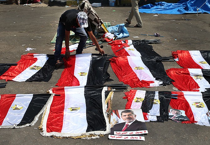 A supporter of ousted Egyptian president Mohammed Morsi arranges Egyptian flags for sale, at Nasr city, in Cairo on Monday. A senior U.S. diplomat has held talks with Egypt's interim president and prime minister-designate in the highest level visit by an American official since the Egyptian military ousted the country's first democratically elected leader. The Arabic on the placard reads, "no alternative to legitimacy."