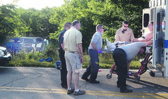Surrounded by officers and Emergency Medical Service professionals, the driver suspected of leading police on an extensive high-speed chase throughout Jefferson City, is loaded into an ambulance, with the wreckage of the vehicle he was driving in the background.  The crash occurred Tuesday evening in the 6000 block of Rainbow Drive where the suspect ran off the road and the vehicle overturned.