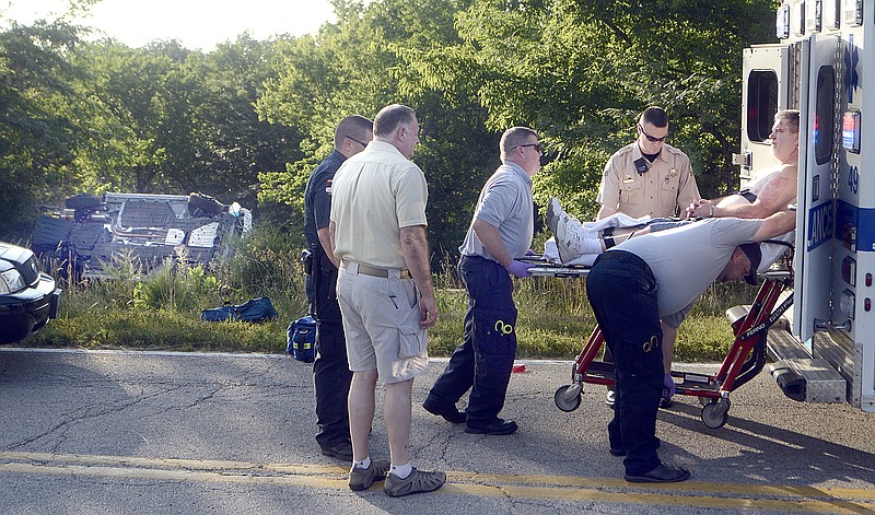 Surrounded by officers and Emergency Medical professionals, the suspect driver of an extensive high-speed chase throughout Jefferson City, is loaded into an ambulance, with the wreckage of the vehicle he was driving in the background. 