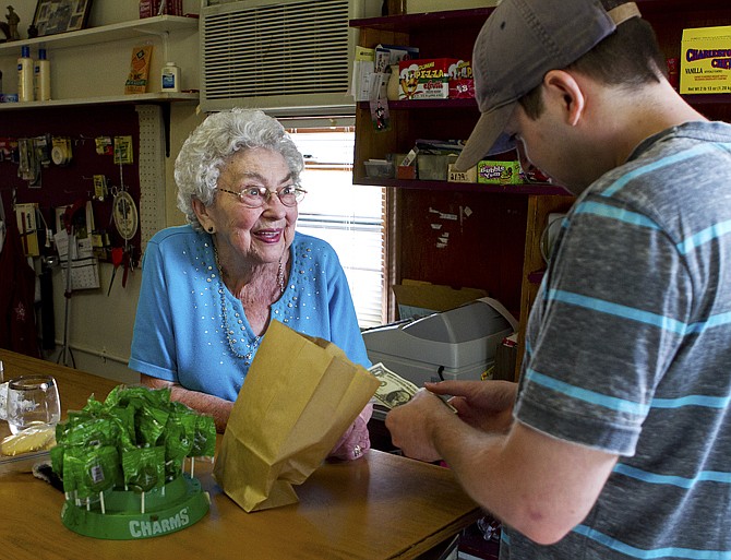 Matt Pilz buys candy from Marge Wolf, 96, at Wolf's Groceries in Marshfield, Wisc., Tuesday, the day after an attempted robbery at knifepoint happened at her store. Wolf refused to open the cash register and the robber eventually left the store upon seeing cameras.