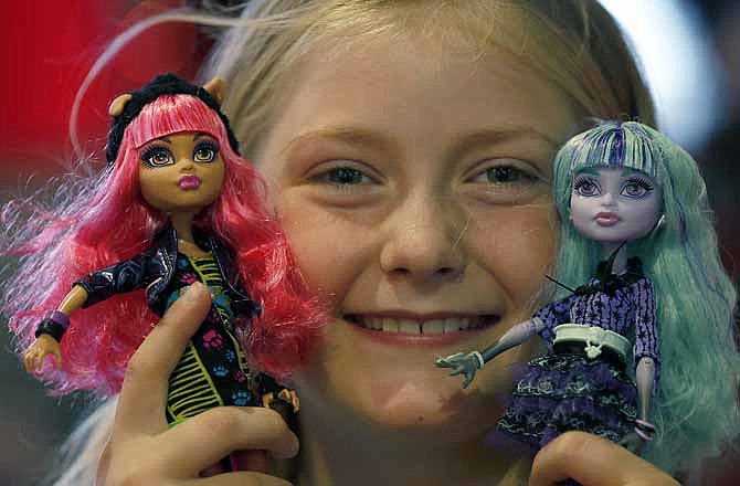In this Thursday, June 27, 2013, photo,Tegan, 9, poses with Monster High Dolls as part of a Christmas toy preview at the toy store Hamleys in London. Mattel's Monster High Dolls, with neon hair and punk clothing, have grown to an estimated $500 million in annual sales since debuting in 2010.