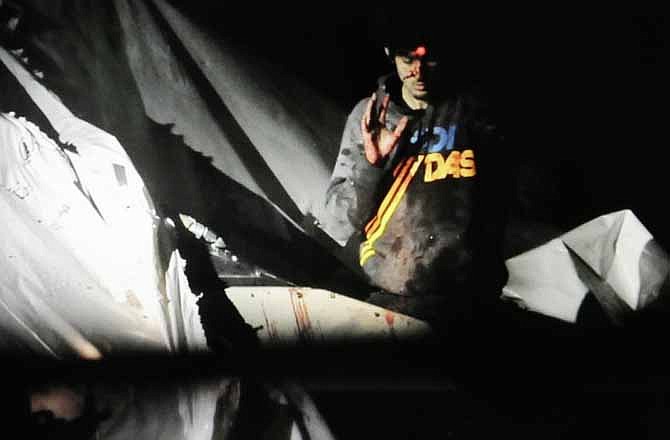 In this Friday, April 19, 2013 Massachusetts State Police photo, 19-year-old Boston Marathon bombing suspect Dzhokhar Tsarnaev, bloody and disheveled with the red dot of a sniper's rifle laser sight on his forehead, raises his hand from inside a boat at the time of his capture by law enforcement authorities in Watertown, Mass.