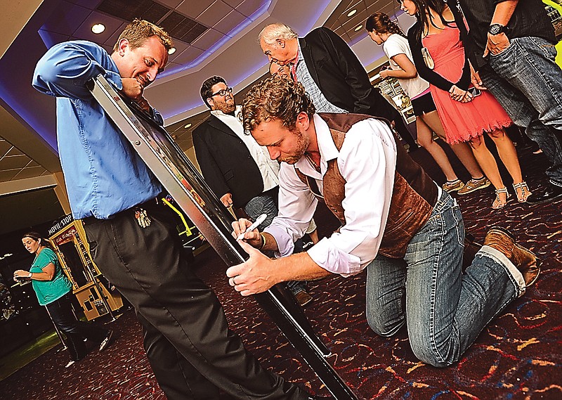 Goodrich Capital 8 manager Bob Wilkins, left, watches as leading actor Jeffrey Johnson autographs an "Apparitional" movie poster following the red carpet premiere of the horror film on Saturday evening.