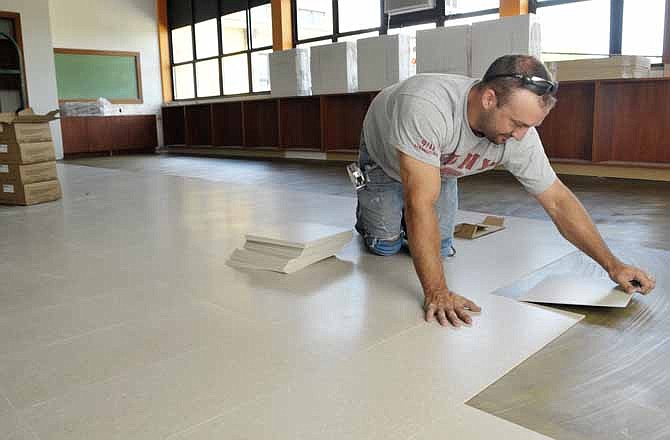 Kevin Allen of Allen Floors puts down tile squares in a first-floor classroom at South School in Jefferson City. Big improvements are being made this summer at the nearly 50-year-old building.