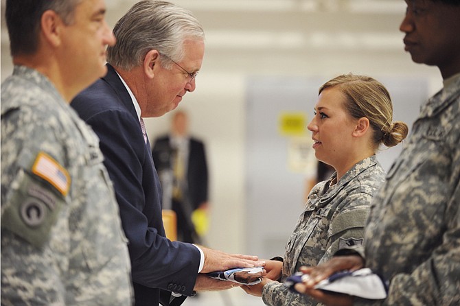 In a Missouri deployment tradition, Gov. Jay Nixon presents the state flag to Col. Mariah Best, the youngest member of the 70th Mobile Public Affairs Detachment. Maj. Gen, Steve Danner, left foreground, presents the U.S. flag to First Sgt. Mary Williams, right, who is the unit's oldest member.