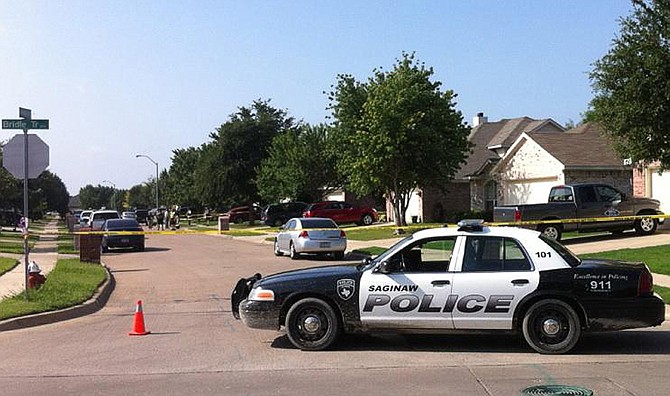 A police car stops traffic Tuesday on Babbling Brook Drive in Saginaw, Texas. A police officer and the suspect were shot in the process of police serving a search warrant two doors from the home of Alanna Gallagher, who was found dead on July 1.