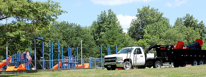 Fulton's city work crews began dismantling a playground Wednesday in Veterans Park near the southwest corner of 10th and Wood streets. Parts of a slide loaded on the truck's trailer came from the blue slide framework at left. Safety issues with playground equipment prompted the Fulton City Council to order the playground closed.