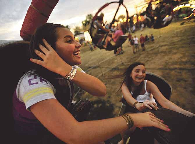 Hailea Davis, left, and Jesi Gladbach are all smiles as they soar through the sky while riding the Tornado at the 2012 Jefferson City Jaycees Cole County Fair.