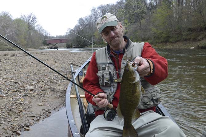 Tim Holschlag, a smallmouth bass fly fishing expert, shows off a nice river smallie he caught on a recent trip.