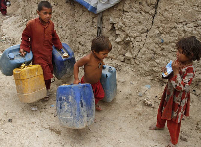 Afghan children carry containers for water Tuesday near their temporary housing on the outskirts of Kabul, Afghanistan. The Pentagon said in a report to Congress that substantial long-term military support will be needed in Afghanistan.