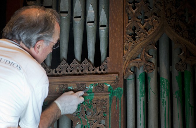 William Adair of Gold Leaf Studios removes green paint from the organ in the Washington National Cathedral's historic Bethlehem Chapel in Washington. Officials at the cathedral discovered the paint inside two chapels Monday afternoon.