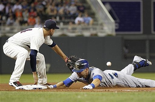Alex Gordon of the Royals slides safely into third with a triple as Twins third baseman Trevor Plouffe waits for the throw during the seventh inning of Wednesday night's game in Minneapolis.