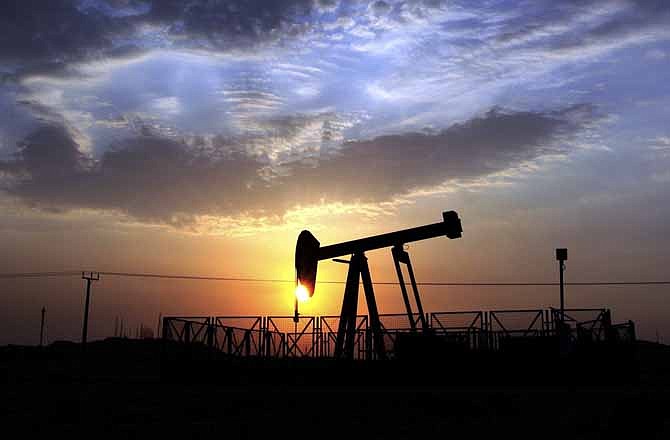 In this Monday Oct. 29, 2012, file photo, an oil pump operates in the desert oil fields of Sakhir, Bahrain, at sunset. New troves of oil are being found all over the globe and each barrel produced is selling for more than $100, as of Thursday, Aug. 1, 2013. But profits and production at the world's biggest oil companies are slumping badly. 