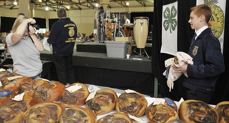 Russellville FFA student Jordan Malzner poses for a photograph in front of the FFA logos before entering the stage. Janice Loesch photographed each student with their cured ham before they sold it. Malzner's blue ribbon ham brought $275 from Cole County Western District Commissioner Kris Scheperle. 