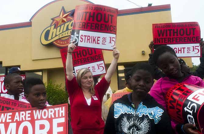 Flint resident Millisa Crossen, 35, center, rallies alongside a few dozen other fast-food workers and area residents during a strike outside of Church's Chicken, Wednesday, July 31, 2013 in Flint, Mich.