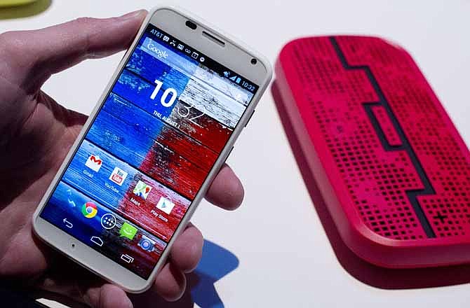 The Motorola Moto X smartphone, using Google's Android software, is displayed, Thursday, Aug. 1, 2013 at a press preview in New York. In the background is a Deck, from Sol Republic, which is a wireless speaker that operates up to 300 feet from the phone using Bluetooth technology.