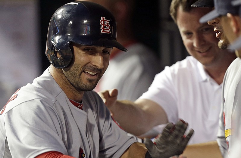 Daniel Descalso is congratulated in the Cardinal dugout after hitting a solo home run during the fifth inning of Friday night's game against the Reds in Cincinnati.