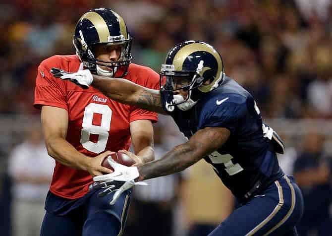 St. Louis Rams quarterback Sam Bradford, left, fakes a handoff to running back Isaiah Pead during an NFL football training camp scrimmage inside the Edward Jones Dome, Saturday, Aug. 3, 2013, in St. Louis. 