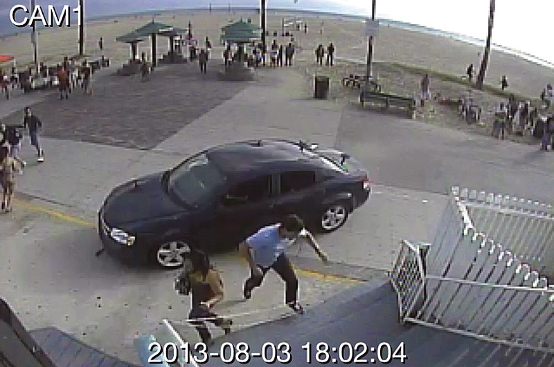 In this still frame made from security camera footage, pedestrians scatter as a car drives through a packed Saturday afternoon crowd along the Venice Beach boardwalk in Los Angeles.