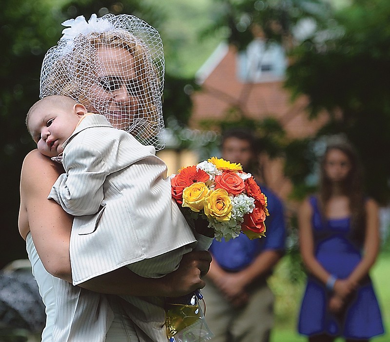 Christine Swidorsky carries her son and the couple's best man, Logan Stevenson, 2, down the aisle to her husband-to-be Sean Stevenson during the wedding ceremony on Saturday.