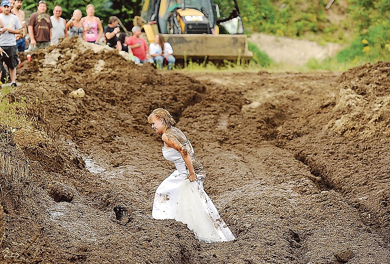 Lucretia (Blais) Gould walks through the mud run pit in her wedding dress after getting married to Jeff Gould at the Redneck "Blank" in Hebron, Maine, on Saturday. Despite being forced to change its name, the event formerly known as the Redneck Olympic Games continued its tradition Saturday.