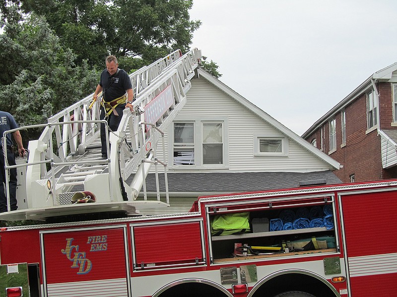 A Jefferson City firefighter grins as he descends a truck ladder after fire and police personnel used it to arrest a suspect hiding on a roof.