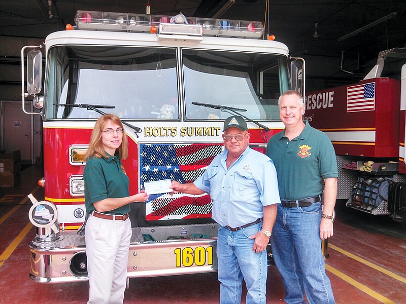 Holts Summit Fire Protection Assistant Chief Lisa Wehmeyer (left) and Assistant Chief Alan Wehmeyer (right) receive a $3,000 grant check from MDC Forestry Resource Agent Ray Crider. The department utilized the matching grant to purchase new pagers to improve their response time to dispatch.