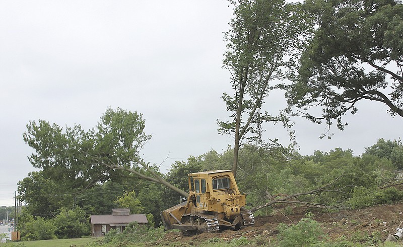 A bulldozer knocks over a tree to make room for expansion at the Danuser plant in Fulton.