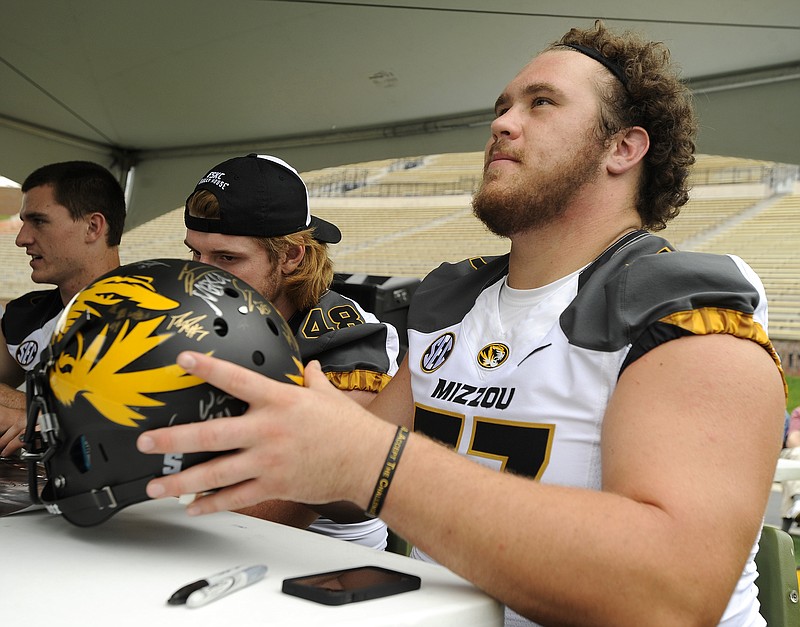 Sophomore offensive lineman Evan Boehm hands a Tiger helmet back to a fan after adding his autograph during Sunday's Mizzou Football Fan Day at Faurot Field in Columbia.