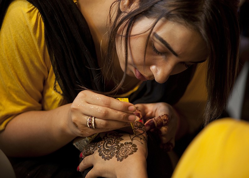 A Pakistani beautician paints a customer's hand Thursday with henna ahead of the Muslim Eid al-Fitr holiday in Islamabad, Pakistan. Pakistani Muslims will start celebrating the Eid al-Fitr holiday today that marks the end of the holy fasting month of Ramadan.