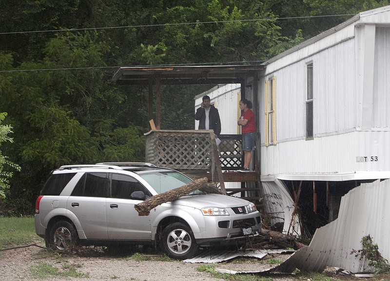 People stand outside a mobile home after a flash flood ripped through a trailer park in Hollister on Thursday morning. Residents of the Hidden Valley Mobile Home Park were rescued and evacuated.  