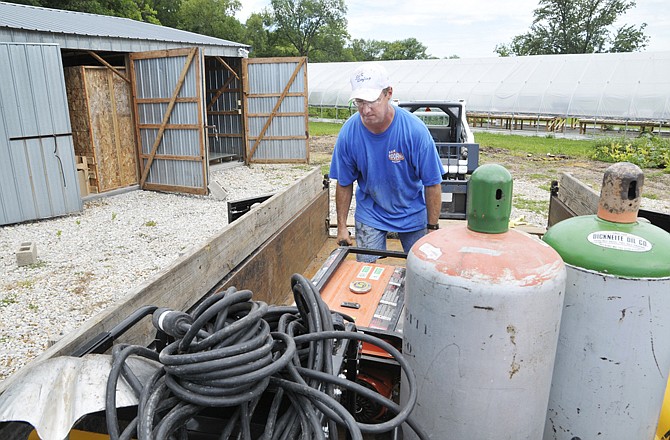 Mark Kloeppel of S&K Roofing cleans out a storage unit Wednesday where the company stores materials used in the company's work. Water was rising rapidly out of the banks of the Maries River in Westphalia, enough so that MoDOT closed the roadway. By the time Kloeppel and others removed the items, water was already over the roadway used to exit the units. Flooding on the Maries River ended Thursday.