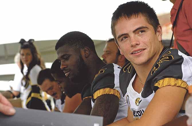 Missouri senior safety Tyler Davis smiles while waiting for Dorial Green-Beckham to finish signing his name and slide another poster down the table to autograph during last week's Fan Day at Faurot Field.