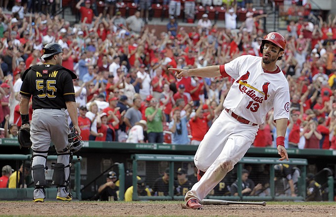 Matt Carpenter of the Cardinals celebrates as he crosses the plate for the game-winning run as Pirates catcher Russell Martin walks off the field after St. Louis' 6-5 victory in 12 innings at Busch Stadium.