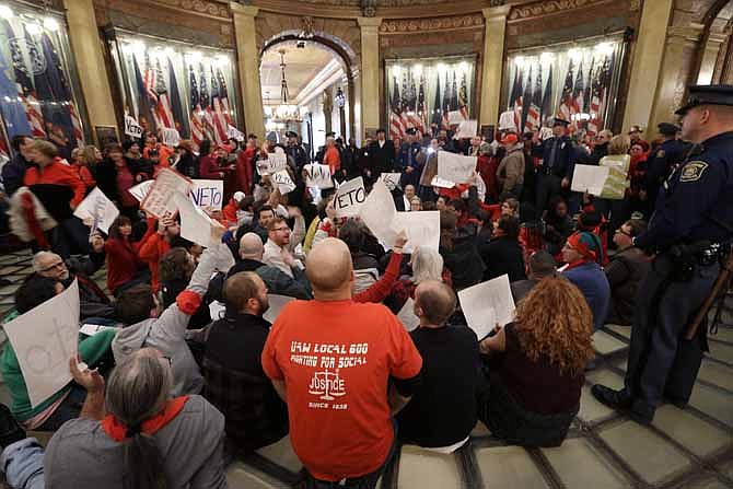 In this Dec. 11, 2012 file photo, protesters sit in the rotunda of the State Capitol in Lansing, Mich., in an unsuccessful effort to block passage of right-to-work legislation that bans labor agreements that require employees to pay fees to the unions that represent them. On Thursday, Aug. 15, 2013, the Michigan Court of Appeals voted 2-1 to uphold a challenge to the law's coverage of 35,000 state employees whose jobs are regulated by the Michigan Civil Service Commission.