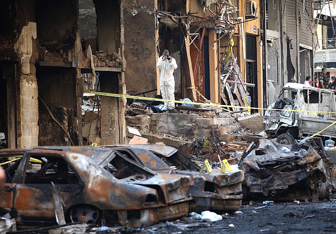 A Lebanese Army investigator, center, takes pictures Friday at the site of a car bomb explosion, in an overwhelmingly Shiite area and stronghold of the Lebanese militant group Hezbollah, in a southern suburb of Beirut, Lebanon.