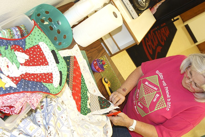 Barb Barnard of Holts Summit cuts a pattern to make a stocking Saturday for the Missouri River Quilt Guild in Jefferson City. The group stitches stockings for charity - work starts now to have enough stockings ready for the holidays.
