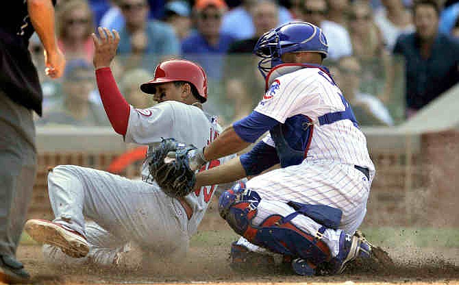 St. Louis Cardinals' Jon Jay left, slides into home plate safely as Chicago Cubs catcher Welington Castillo right, tries to apply the tag during the fifth inning of a baseball game in Chicago, Saturday, Aug. 17, 2013.