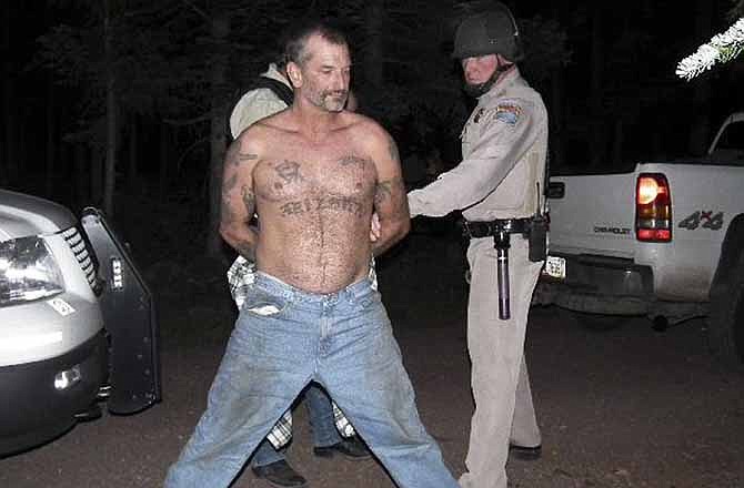 In this Aug. 19, 2010 file photo provided by the U.S. Marshals Service, fugitive John McCluskey is taken into custody by U.S. Marshals in eastern Arizona. On Monday, Aug. 19, 2013, McCluskey, the last of the three people charged with killing Gary and Linda Haas of Tecumseh, Okla., goes to trial, accused in their 2010 carjacking and shooting deaths.