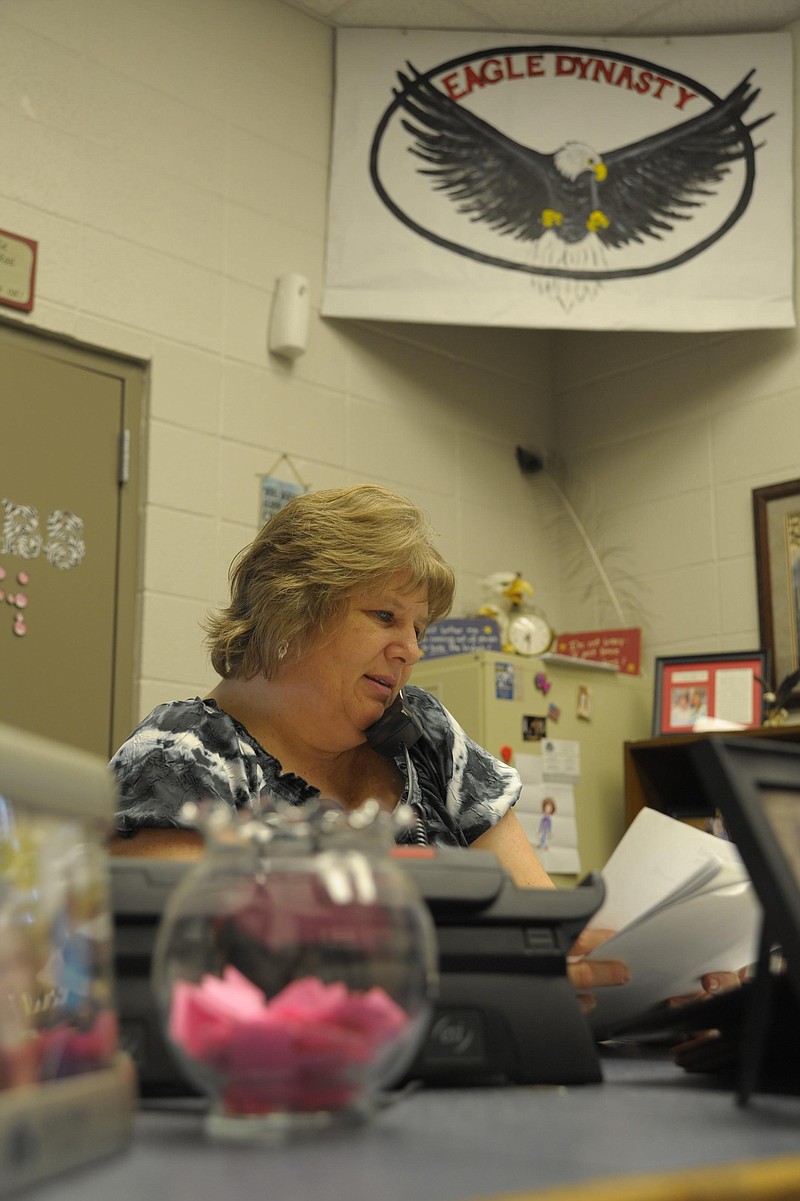 Eugene High School secretary Vonda Berendzen shuffles through papers while answering the phone. She makes no secret of the fact she makes the students her top priority.