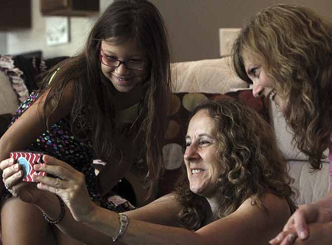 Makenna Barnes,7, shows vacation photos on an iPhone to grief therapists Diane Castro and Jennifer Lang with Wings on Wheels expressive grief therapy program during a visit on Tuesday, July 16, 2013, at their home in St. Peters, Mo. 