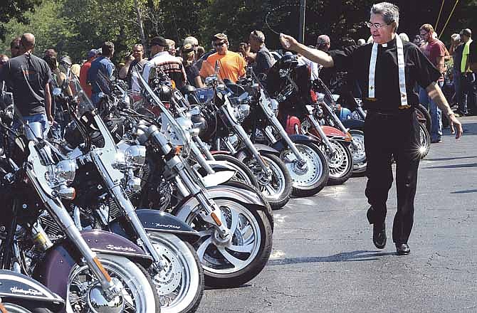 Father Ignazio Medina, a priest from the St. Stanislaus Parish in Wardsville, Mo., blesses the motorcycles and riders that participated in the 6th annual Poker Run for Veterans, which started out from the parking lot of the Elk's Lodge.