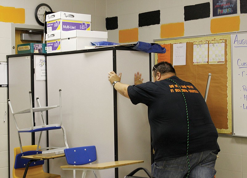 Jeff Cowart, a Junior High School social studies teacher, shoves portable cases filled with heavy books against the door of his classroom during a drill Tuesday simulating an armed intruder firing shots in the New Bloomfield High School.
